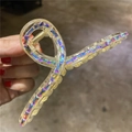 Dettaglio di una grande pinza per capelli trasparente con strass colorati in mano - Trasparente