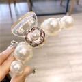 Gros plan sur la grande pince à cheveux camélia avec perles élégantes et crème - Camélia Blanc