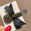 Dettaglio del fermaglio per capelli con fiocco nero decorato con strass scuri e clip a becco - Fiocco a Una Pietra