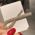 Détail d'une pince à cheveux dorée en forme de X ornée de strass brillants pavés - Style croisé doré