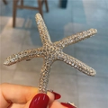 Gros plan détaillé d'une pince à cheveux étoile de mer avec strass étincelants sur alliage doré - Étoile de Mer Or