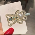Dettaglio di un fermaglio a farfalla con strass e una perla bianca a forma di cuore - Orso Dorato