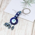 Dettaglio dei ciondoli Evil Eye in vetro fatti a mano con corda intrecciata blu su legno - Portachiavi Occhio Blu Turco
