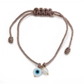 Detail of woven rope bracelet featuring a blue evil eye bead and a freshwater pearl charm - Gray