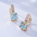 Detail of square light blue gemstone earrings with gold finish and micro-inlaid diamonds - Lake Blue