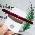 Vue détaillée d'une barrette à cheveux rouge foncé brillante sur carte blanche - Bordeaux