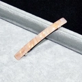 Detailed close-up of marble pink and yellow acetate spring hair clip on gray velvet tray - Orange Floral