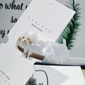 Detail of a white marble acetate cat hair clip displayed on a branded jewelry card - Marbled White Cat Style / White
