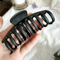 Pinza grande para el pelo en negro mate para cabello grueso, mostrada en una mano - Negro