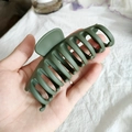 Mano sosteniendo una pinza de pelo grande verde oscuro mate para peinados de pelo grueso - Verde Militar