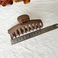Détail de la grande pince à cheveux mate marron de 11 cm à côté d'une règle métallique - Marron