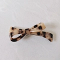 Detail of a minimalist hair clip with a leopard print bow design and glossy finish - Light Color