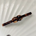 Eleganter Haarclip aus Acetat mit Schildpattmuster und Knotendetail auf weißem Grund - Dunkler Leopard