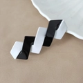 Detailaufnahme einer geometrischen schwarz-weißen Haarspange mit glänzendem Finish - Schwarz Weiß