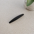 Nahaufnahme der minimalistischen mattschwarzen Haarspange mit matter Textur auf beigem Stoff - Schwarz