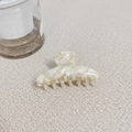 Dettaglio ravvicinato della molletta in acetato con texture marmo crema lucida - Stile Bianco Floreale