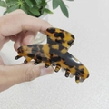 Dettaglio di una grande pinza per capelli in acetato con motivo tartarugato tenuta in mano - Stile Tartarugato Scuro