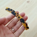 Vista dettagliata di un fermaglio per capelli lungo curvo in acetato con motivo leopardo - Leopardo Scuro