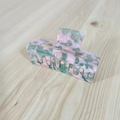 Primer plano de una pinza para el pelo de acetato jaspeado rosa y verde sobre madera - Floral Verde Rosa