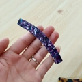 Nahaufnahme der Bananenspange aus Acetat mit lila Marmormuster in der Hand gehalten - Violettes Blumenmuster