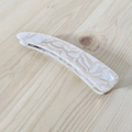Dettaglio di un fermaglio per capelli a banana in acetato marmorizzato dal design curvo - Floreale Crema