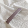 Close-up of minimalist Morandi purple hair clip with a glossy finish on white fabric - Taro