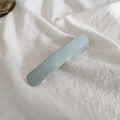 Glossy light blue rectangular hair clip shown on white textured fabric for hair styling - Bean Green