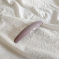 Detail view of a minimalist grey-purple glossy spring hair clip on white textured fabric - Taro