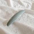 Close-up of minimalist Morandi grey-blue glossy spring hair clip on white fabric - Bean Green
