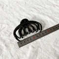 Makroaufnahme einer 8cm glänzenden schwarzen Haarklammer mit Lineal auf weißem Stoff - Glänzend Schwarz