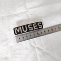 Détail de la barrette MUSES en strass noirs sur un tissu blanc à texture fine - Noir