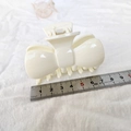 Close-up of a cream white bow hair claw clip measured at 8.5cm with a steel ruler - Off White
