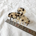 Detalle de una pinza para el pelo con estampado de leopardo sobre un fondo de tela blanca - Color Claro