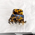 Detalle de pinza para el cabello con estampado de carey y leopardo sobre tela blanca - Color Oscuro