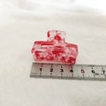 Détail d'une pince à cheveux en acétate marbré rouge et blanc de 4,2 cm avec échelle - Série Rouge