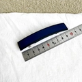 Pasador rectangular azul mate de 9,3 cm de largo sobre fondo de tela blanca fina - Azul marino