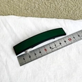 Detalle de una pinza para el pelo rectangular de 10cm verde oscuro sobre tela blanca - Verde Militar