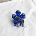 Macro shot of blue floral acetate hair claw clip on white fabric with marble pattern - Blue Floral