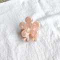 Detailed top view of a peach pink flower hair claw clip with marble texture on white fabric - Pink Floral