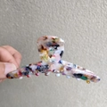 Primer plano de pinza para el pelo de acetato colorido con patrón terrazo y agarre firme - Flores de Colores
