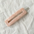 Detalle de pinza para el pelo en acetato rosa jaspeado sobre fondo de tela blanca - Rosa