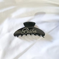 Detail view of large black acetate hair claw clip with sparkling rhinestone Babe letters - Black