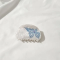 Nahaufnahme der halbrunden Harz-Haarklammer mit blauem Strass-Schmetterling und lila Stein - Weiß