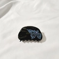 Nahaufnahme der schwarzen Haarklammer mit blauem Strass-Schmetterling und lila Edelstein - Schwarz