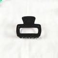 Detalle de una pinza para el pelo cuadrada en acetato negro brillante sobre tela - Negro