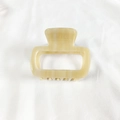Close-up of a small square acetate hair claw clip in creamy yellow on white fabric - Beige Marble
