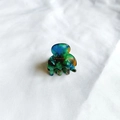 Close-up of a mini acetate hair claw clip with colorful marble texture on white fabric - Green Pattern