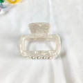 Detail of a square cream marble acetate hair claw clip on white linen fabric - White