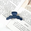 Macro shot of matte dark blue round hair claw clip on an open book background - Navy Blue