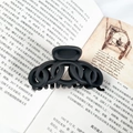 Gros plan d'une pince à cheveux noire mate au design de chaîne sur des pages de livre - Noir